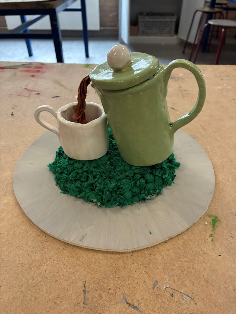 Leerlingwerk voor de opdracht Rotondekunst: een groen koffiekan-kunstwerk op een maquette